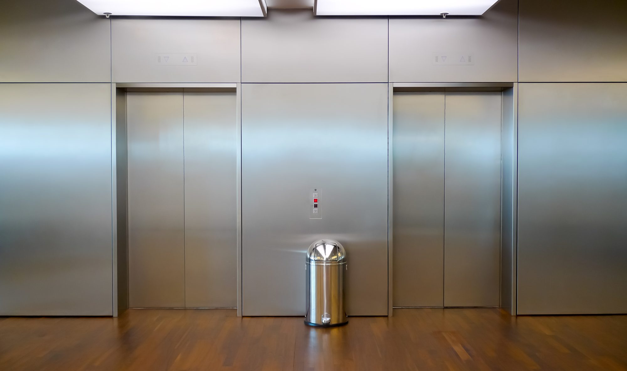 Two brushed metal elevator doors in a minimalistic style building interior